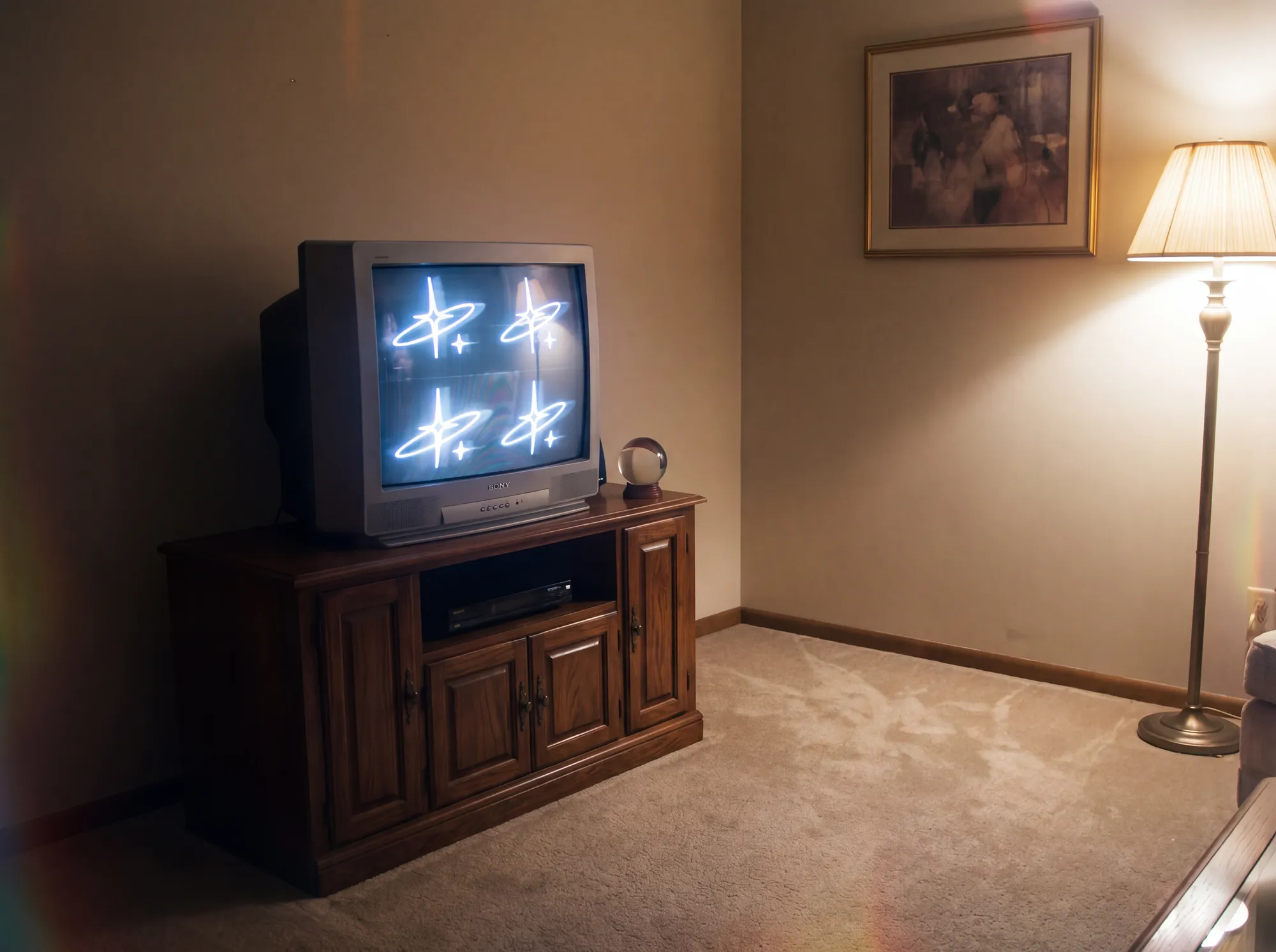 A brand sigil — a four-point star crossed by an orbit — glowing four-up on a vintage CRT television in a warmly lit, beige living room.